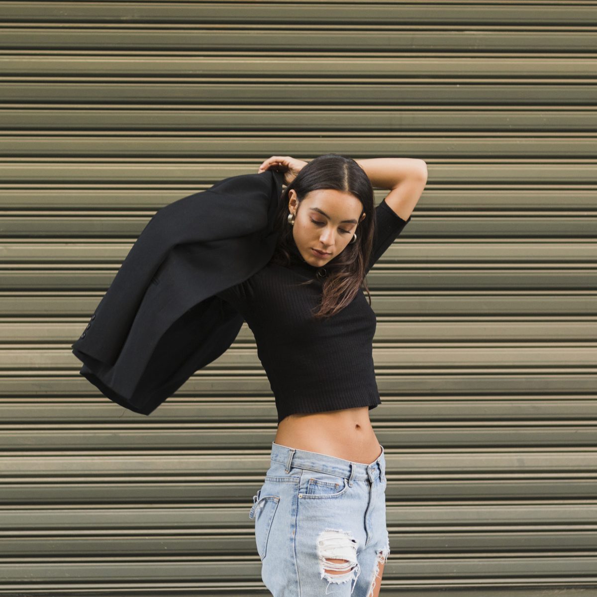 young woman standing front green shutter wearing coat (1)